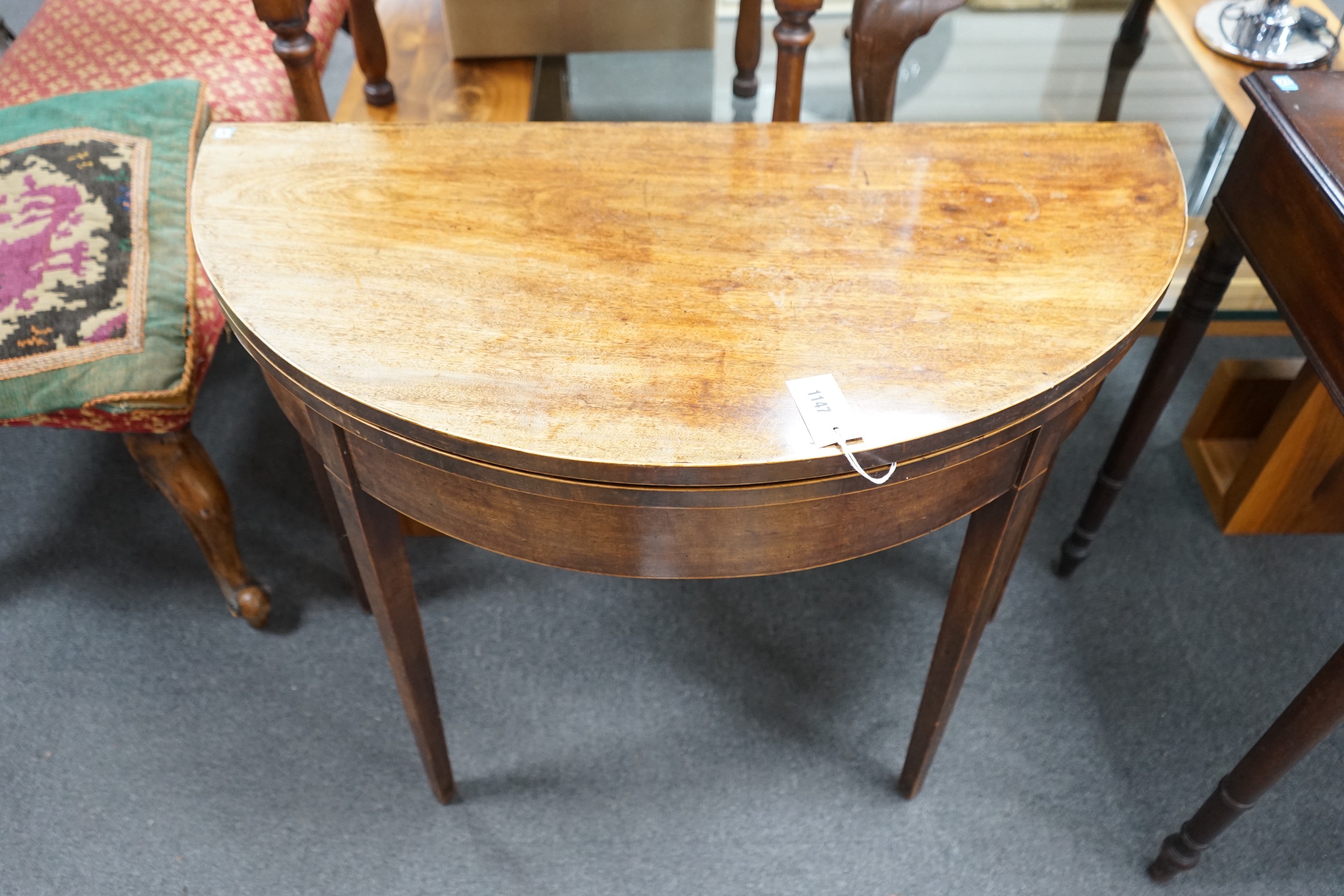 A George III mahogany and boxwood strung D shaped folding card table, width 91cm, depth 45cm, height 74cm